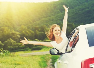 happy woman looks out the car window on nature summer